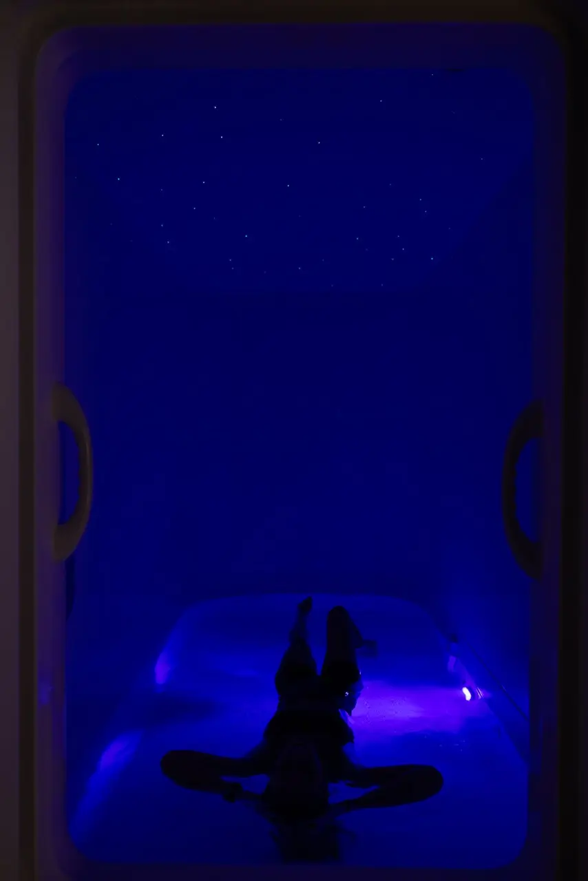 Guest floating in the pod under blue light, with star lights overhead