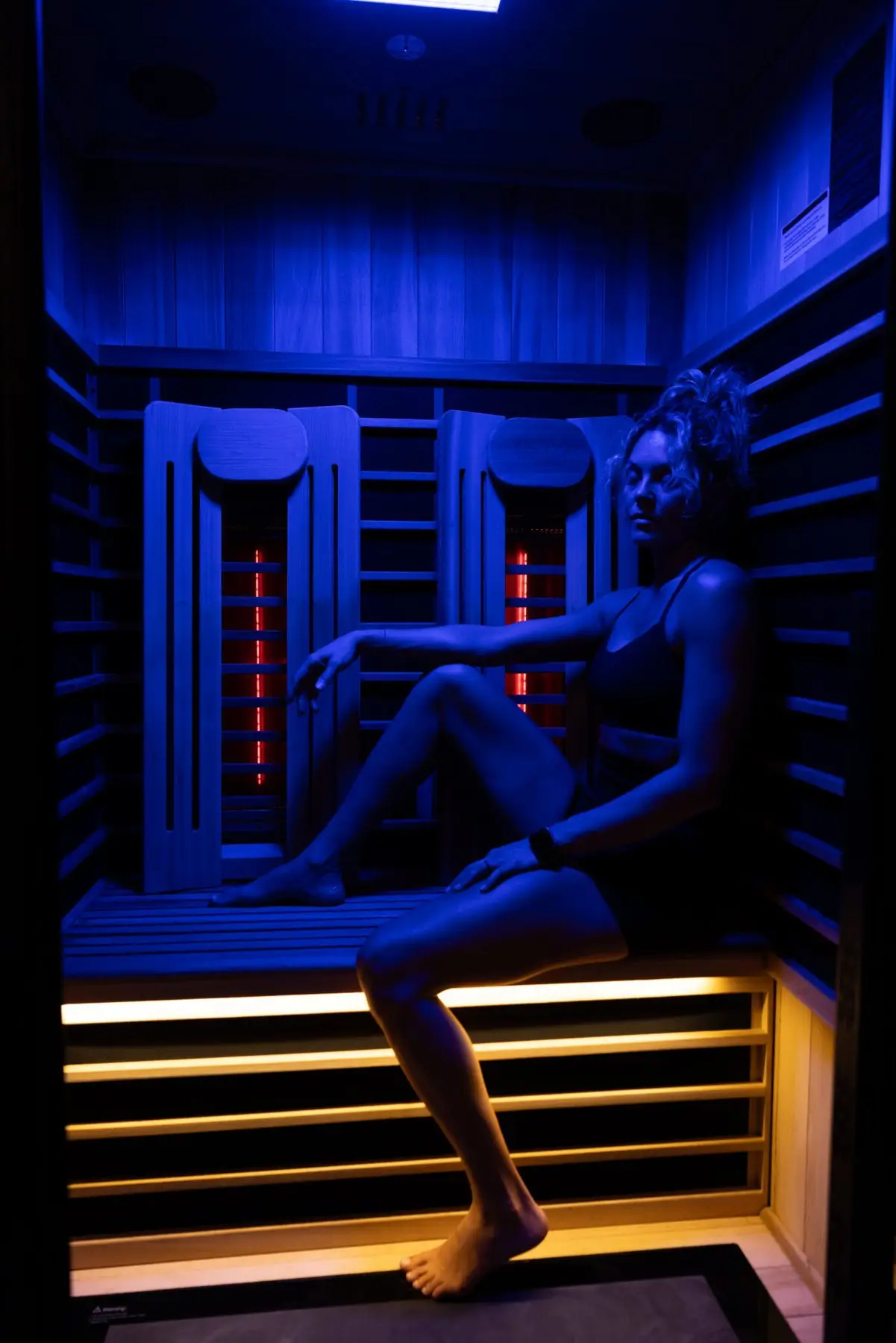 Guest seated in the sauna under blue light