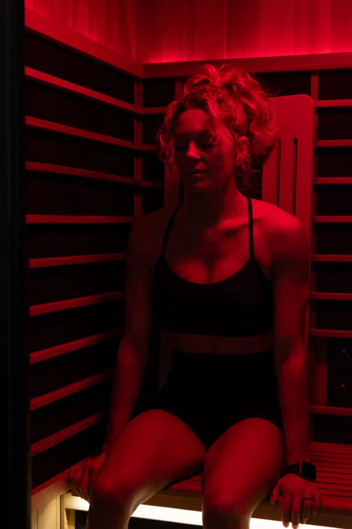 Guest seated in the infrared sauna under red light